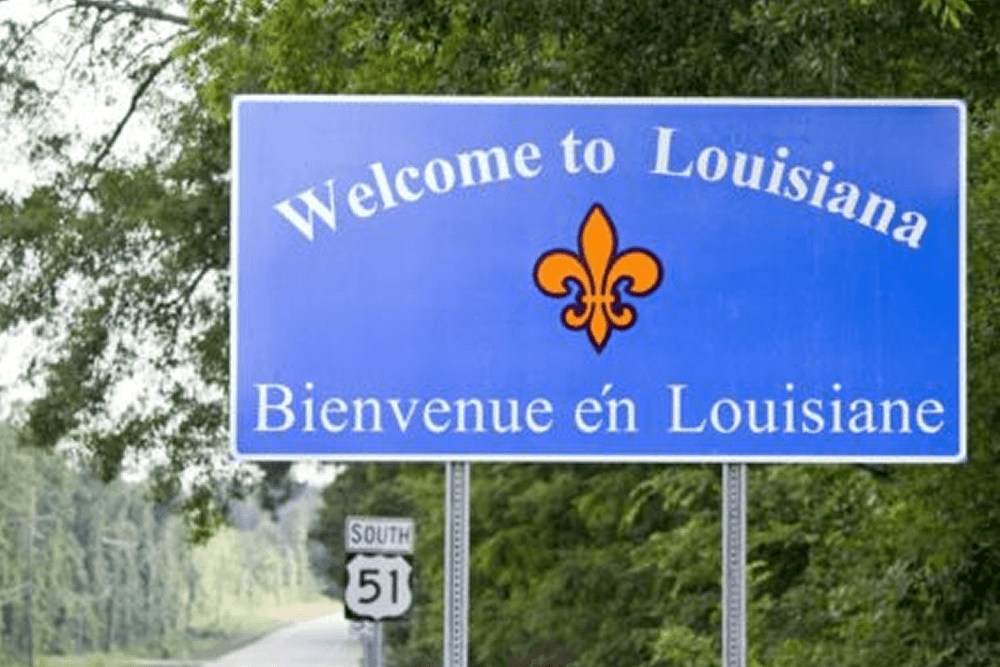 A blue road sign welcoming visitors to Louisiana, featuring the text "Welcome to Louisiana" and "Bienvenue en Louisiane."