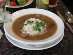 A bowl of rice in a flavorful brown broth, garnished with green herbs.