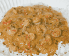 A plate of shrimp in creamy sauce served over white rice.